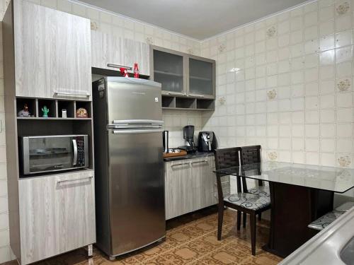 Il comprend une cuisine équipée d'un réfrigérateur en acier inoxydable et d'une table. dans l'établissement Sobrado bem próximo ao Aeroporto, à Guarulhos