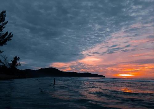 a person is standing in the water at sunset at Borneo Beach Villa & Suite in Kota Kinabalu