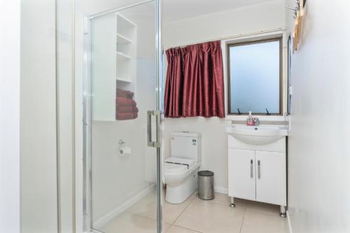 La salle de bains est pourvue de toilettes, d'un lavabo et d'un miroir. dans l'établissement Grange Motel, à Auckland