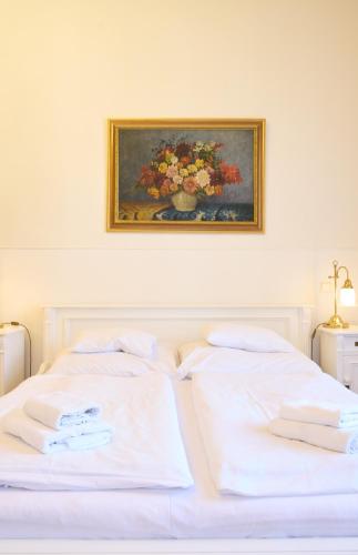 a bedroom with a white bed with a painting on the wall at Hotel U Zlateho jelena in Prague