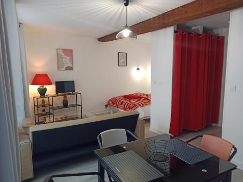 a living room with a red curtain and a bedroom at Studio Zoé in Saint-Père