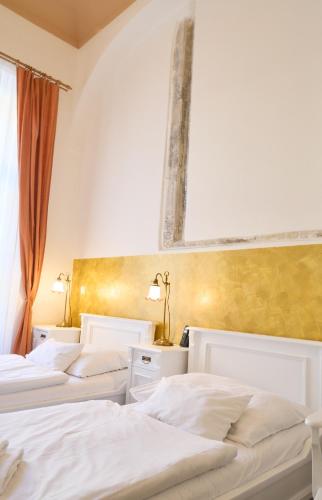 three beds in a hotel room with white sheets at Hotel U Zlateho jelena in Prague