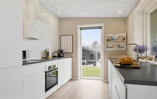 a kitchen with white cabinets and a large window at Three-Bedroom Holiday Home In Haderslev in Haderslev