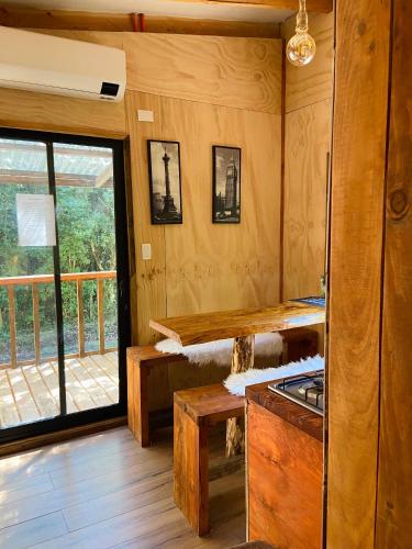 a kitchen with wooden walls and a large window at Cabañas Los Glaciares in Coñaripe