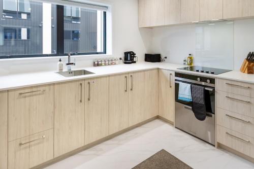 eine Küche mit Holzschränken und einem Fenster in der Unterkunft Style meets comfort 2 Bed CHCH CBD in Christchurch