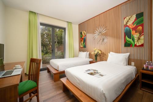 a bedroom with two beds and a desk and a computer at Co Villas in Hoi An