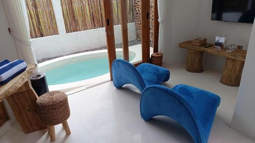 a room with a pool with blue chairs and a table at Sangkar Cottage & Eatery in Seturan