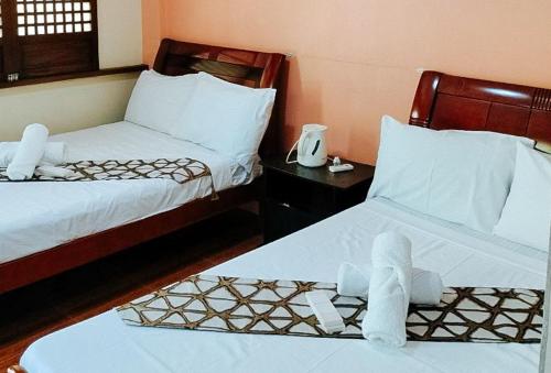 two beds in a hotel room with towels on them at RedDoorz @ Hilarion's Farm Majayjay, Laguna in Majayjay