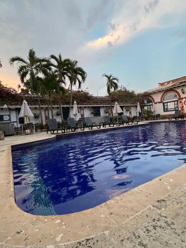 uma piscina num resort com cadeiras e palmeiras em Hotel Villa María Santa Fe de Antioquia em Santa Fe de Antioquia