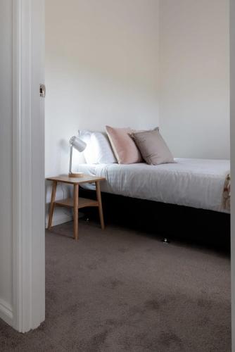 a bed with pillows and a table with a lamp at Perfect for Groups or Families in Prospect in Kings Meadows