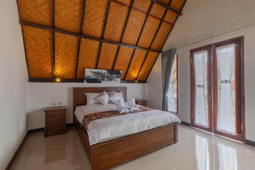 a bedroom with a bed and a large window at Maskot Penida Cottage in Nusa Penida