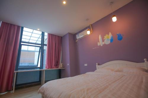 1 dormitorio con cama blanca y pared morada en Ningbo 238 International Youth Hostel, en Ningbo