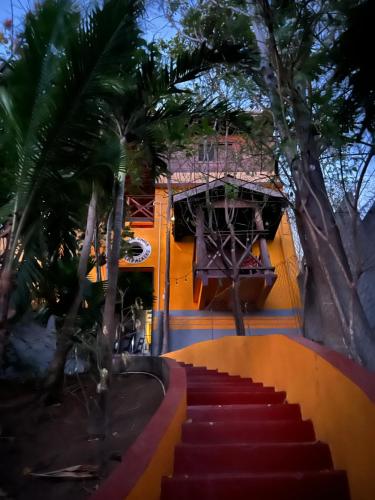 a flight of red stairs with trees and a building at Buena Onda Backpackers in San Juan del Sur