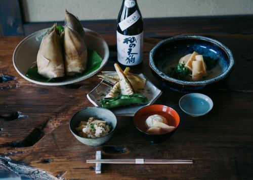 einem Holztisch mit Schüsseln aus Essen und einer Flasche in der Unterkunft 福田屋 in Imazu