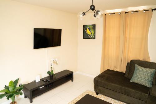 a living room with a couch and a flat screen tv at Sunset Cove Barbados in Christ Church