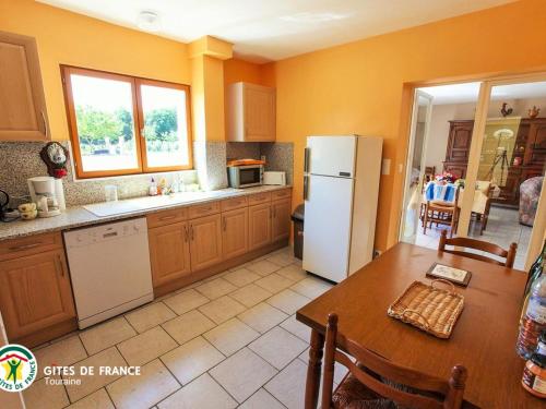 une cuisine avec une table et un réfrigérateur blanc dans l'établissement Longère authentique avec jardin privé, près des Châteaux de la Loire, idéale pour familles et nature - FR-1-381-501, à Saint-Laurent-de-Lin