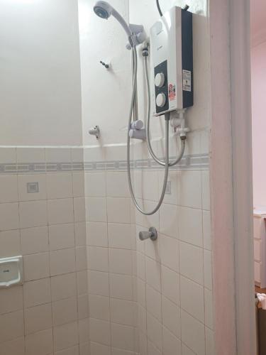 a shower in a bathroom with white tiles at Butterworth Seaside view Family spacious in Butterworth