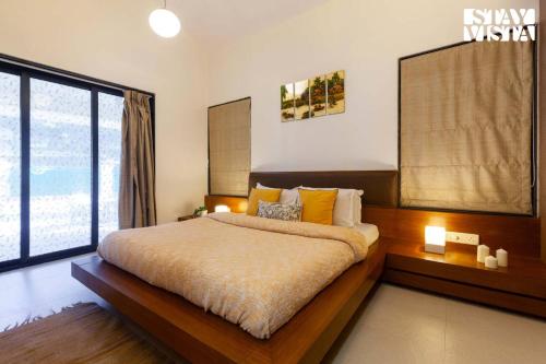 Un dormitorio con una cama grande y una ventana grande. en Eden's Estate by StayVista - Featuring cozy rooms with a private pool, and modern interiors for a delightful stay, en Alibaug
