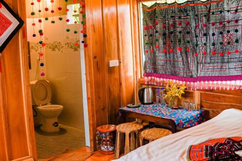 een slaapkamer met een bed, een tafel en een toilet bij Homestay Chu Vang in Phong Thổ