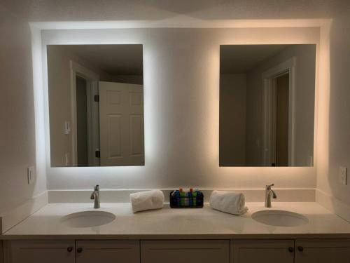 two sinks in a bathroom with two mirrors at West Beach Suites in Lincoln City