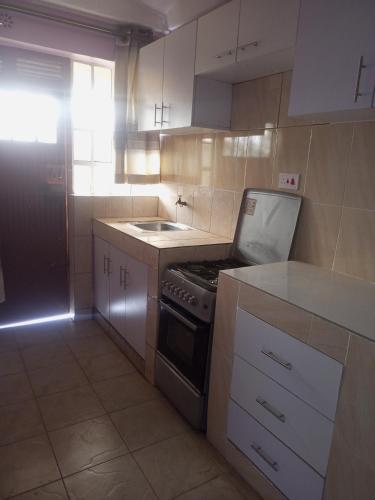 a small kitchen with a stove and a refrigerator at Verona Apartments in Thika