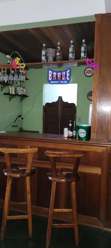 a bar with two wooden stools at a bar at Ninho dos Passaros Penedo RJ in Penedo