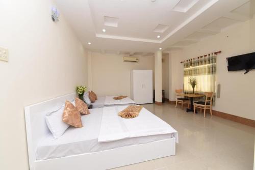 Habitación blanca grande con 2 camas y mesa. en Khách sạn Đồng Tháp - Hoàng Gia Minh Lợi en Mỹ An
