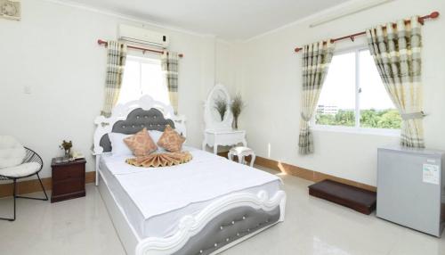 um quarto com uma cama branca e uma televisão em Khách sạn Đồng Tháp - Hoàng Gia Minh Lợi em Mỹ An