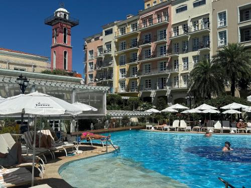 una piscina di fronte a un edificio con torre dell'orologio di Destino Floripa Jurerê In a Florianópolis