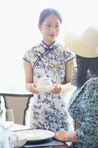 a woman is holding a piece of cake at Shangri-La Qinhuangdao in Qinhuangdao