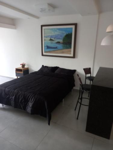 a bedroom with a black bed and a table and chair at Suíte do Betão in Mangaratiba