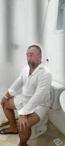 Ein Mann, der auf einer Toilette im Badezimmer sitzt. in der Unterkunft Areia Branca Casas / casa 1. in Cabo Frio