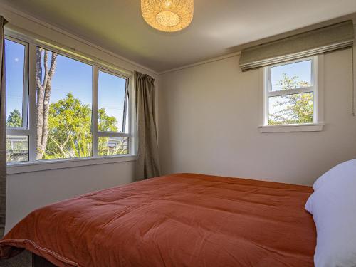 a bedroom with a large bed and two windows at Alpine Rest - National Park Holiday Home in National Park