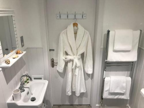 a white robe hanging on a door in a bathroom at The Hut- Private 1 Bed Guesthouse in Lymington Town Centre, garden & parking in Lymington