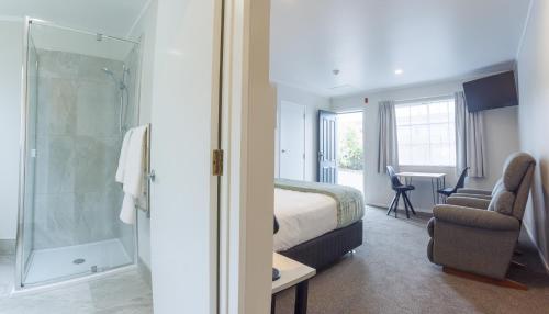 una camera d'albergo con letto e doccia di BK's Pohutukawa Lodge a Whangarei
