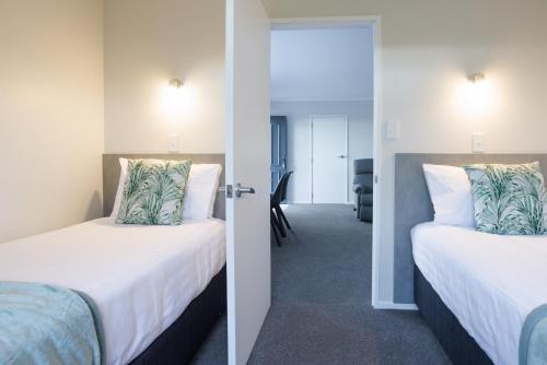 duas camas num quarto de hotel com um corredor em BK's Pohutukawa Lodge em Whangarei