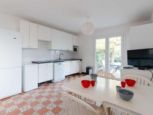 une cuisine avec des appareils blancs et une table avec des chaises dans l'établissement Appartement T2 en RDC, 6 pers, Narbonne-Plage, 100m de la mer, animaux OK, cuisine équipée, WiFi - FR-1-409-149, à Narbonne