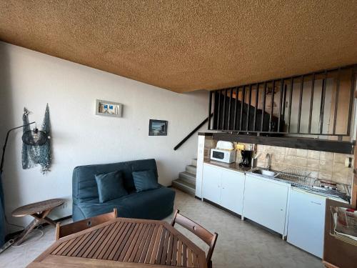 un salon avec un canapé bleu et une table dans l'établissement Arcachon Aiguillon - Duplex T1 à deux pas de la plage - FR-1-319-71, à Arcachon