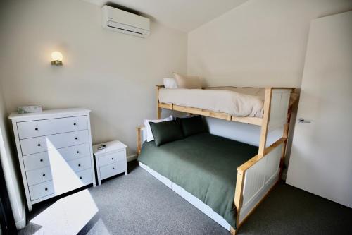 a small bedroom with a bunk bed and a dresser at Hamilton By the Bay 3 Newly Built in Safety Beach