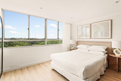 una camera bianca con un grande letto e ampie finestre di Chic Studio with a Pool and Moments from Shop a Sydney