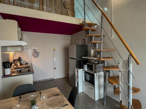 une cuisine avec un escalier et une salle à manger avec une table dans l'établissement Duplex convivial à Saint-Cyprien - 4 couchages - Plage & commerces à pied - FR-1-753-16, à Saint-Cyprien