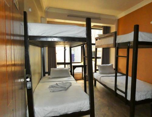 Habitación con 3 literas y sábanas blancas. en Paradise Guest House, en Katmandú