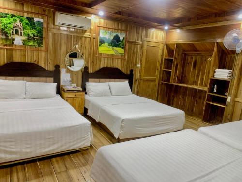 three beds in a room with wooden walls at Hang Lan Bungalow in Ninh Binh