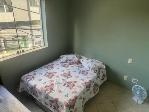 a small bedroom with a bed with a floral blanket at Apart Hotel big john 101 Vista para rua in Divinópolis