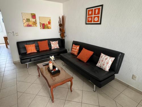 a living room with a black couch and a coffee table at Acapulco diamante departamento con playa ecológico in Acapulco