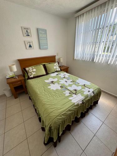 - une chambre dotée d'un lit avec un couvre-lit vert et des fleurs dans l'établissement Acapulco diamante departamento con playa ecológico, à Acapulco