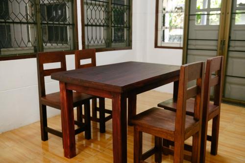 einen hölzernen Esstisch und Stühle mit Buntglasfenstern in der Unterkunft Nadee House in Ban Pa Sang (1)