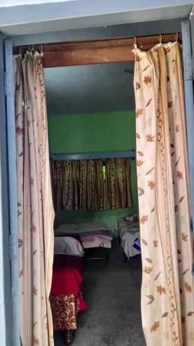 Zimmer mit 2 Betten und einem Fenster mit Vorhängen in der Unterkunft Karunanidhan Homestays in Ayodhya