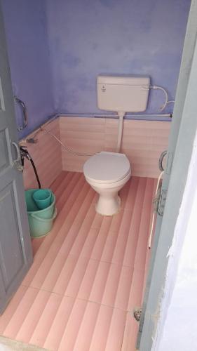 a bathroom with a toilet in a pink room at Karunanidhan Homestays in Ayodhya