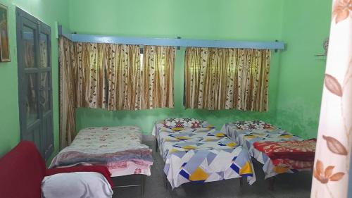 2 Betten in einem Zimmer mit grünen Wänden und Vorhängen in der Unterkunft Karunanidhan Homestays in Ayodhya